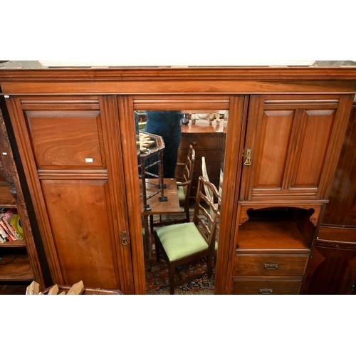 223 - An Edwardian walnut compactum wardrobe with mirrored door enclosing brass rail beside panelled cupbo... 