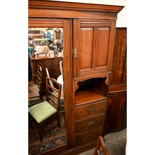 223 - An Edwardian walnut compactum wardrobe with mirrored door enclosing brass rail beside panelled cupbo... 