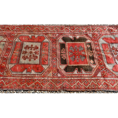 237 - A vintage Kurdish red ground runner with seven octagonal medallions, 440 x 93 cm (extreme woof/curve... 