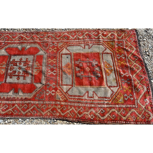 237 - A vintage Kurdish red ground runner with seven octagonal medallions, 440 x 93 cm (extreme woof/curve... 