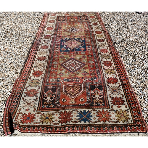 255 - An old Caucasian wide runner of geometric design on terracotta ground with cream border, 288 x 116 c... 