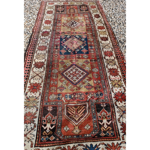 255 - An old Caucasian wide runner of geometric design on terracotta ground with cream border, 288 x 116 c... 