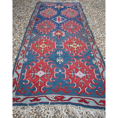 256 - A vintage Turkish Kilim, red 'hooked' medallions on blue field, 300 x 123 cm