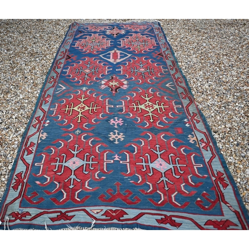 256 - A vintage Turkish Kilim, red 'hooked' medallions on blue field, 300 x 123 cm