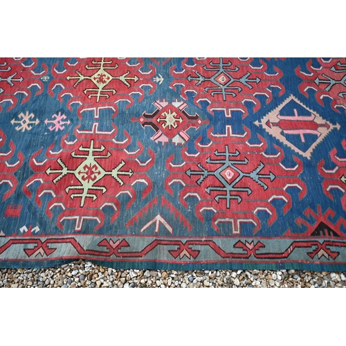 256 - A vintage Turkish Kilim, red 'hooked' medallions on blue field, 300 x 123 cm