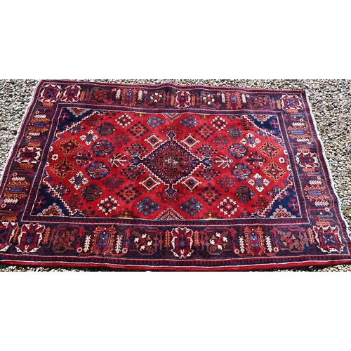 259 - A Persian Bijar rug, the central diamond medallion and floral motifs on red ground with dark blue bo... 