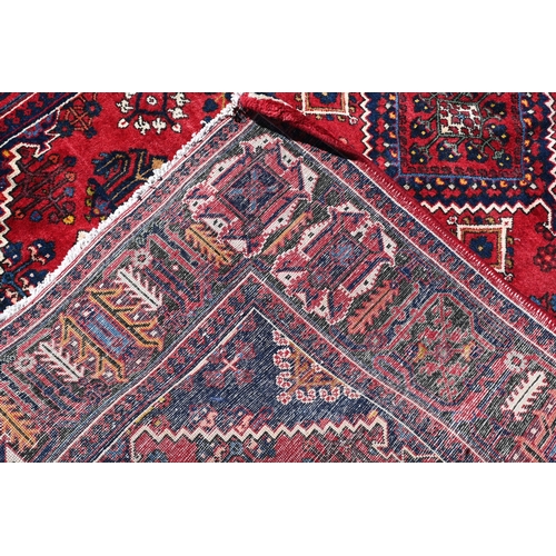 259 - A Persian Bijar rug, the central diamond medallion and floral motifs on red ground with dark blue bo... 