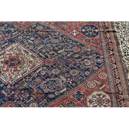 262 - A worn Persian Shiraz kelleigh rug, beige diamond medallion and stylised floral design on blue groun... 