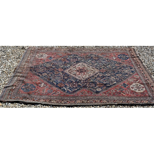 262 - A worn Persian Shiraz kelleigh rug, beige diamond medallion and stylised floral design on blue groun... 