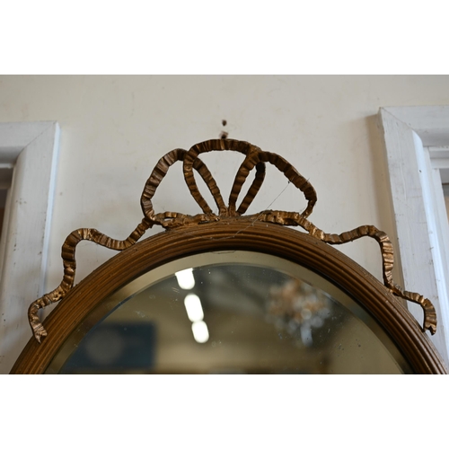 276 - # A bevelled oval mirror in giltwood and gesso ribbon crested frame, 44 cm wide x 64 cm high