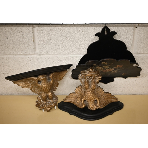 509 - A pair of ebonised and gilt composite wall brackets supported by spread eagles 31 cm wide, to/w a fo... 