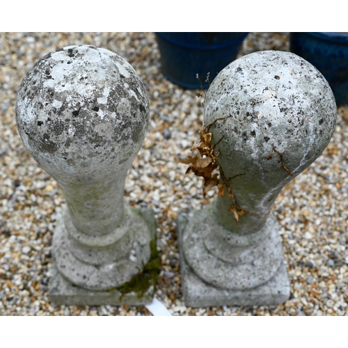 65 - A pair of weathered cast stone ball finials raised on associated square plinth bases (2)