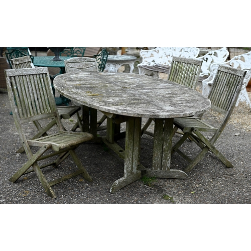 73 - A weathered teak garden table, oval to.wirh four folding chairs and another differing chair, all a/f... 