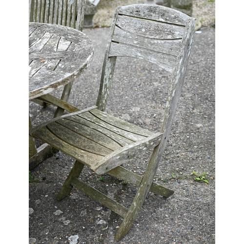 73 - A weathered teak garden table, oval to.wirh four folding chairs and another differing chair, all a/f... 