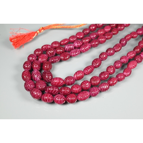 343 - A triple row of graduated carved ruby beads on silk cord, 1 x 0.8 cm the smallest, 1.5 x 1.3 cm the ... 