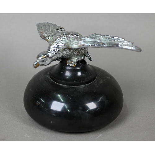 953 - A vintage chrome spread eagle car mascot, 4 cm high x 18 cm wingspan, mounted on a turned stone plin... 