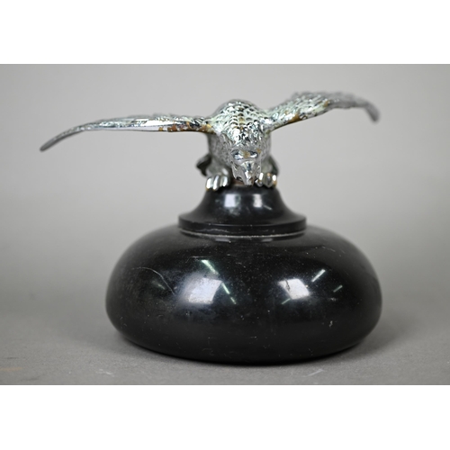 953 - A vintage chrome spread eagle car mascot, 4 cm high x 18 cm wingspan, mounted on a turned stone plin... 