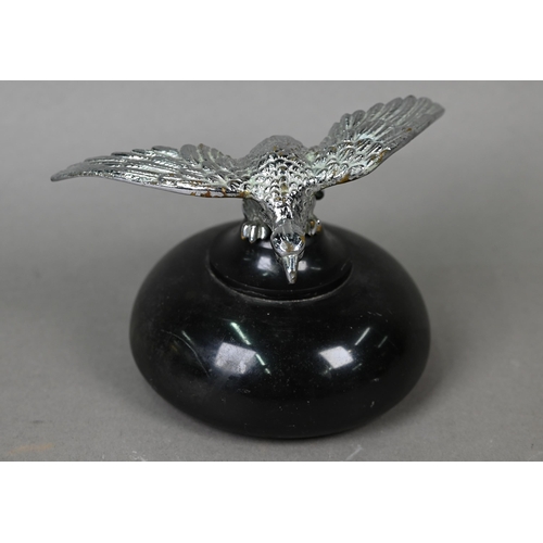 953 - A vintage chrome spread eagle car mascot, 4 cm high x 18 cm wingspan, mounted on a turned stone plin... 