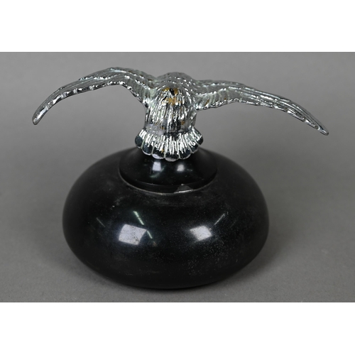 953 - A vintage chrome spread eagle car mascot, 4 cm high x 18 cm wingspan, mounted on a turned stone plin... 