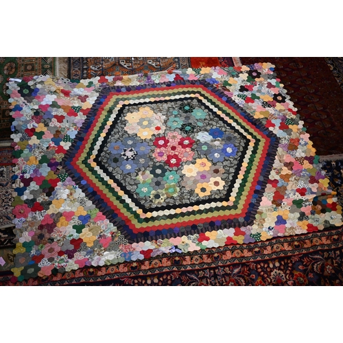 763 - A vintage patchwork bedspread of rectangular form, featuring handstitched hexagonal patches, some pe... 