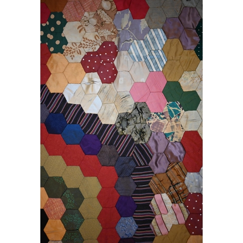 763 - A vintage patchwork bedspread of rectangular form, featuring handstitched hexagonal patches, some pe... 