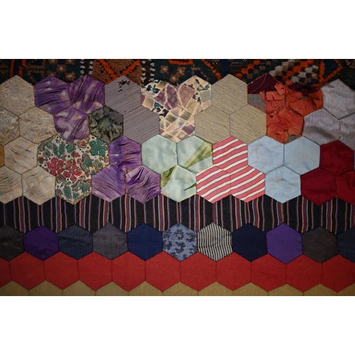 763 - A vintage patchwork bedspread of rectangular form, featuring handstitched hexagonal patches, some pe... 