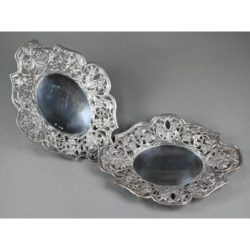 131 - A pair of Victorian silver oval dishes with richly embossed and pierced floral and foliate borders, ... 