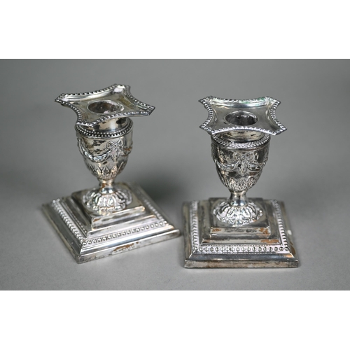 158 - A pair of late Victorian loaded silver Adam Revival short candlesticks of urn form, embossed with sw... 