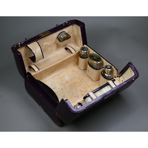 177 - An Asprey puce Morocco leather dressing case, fitted with five cut glass toilet jars - four with sil... 