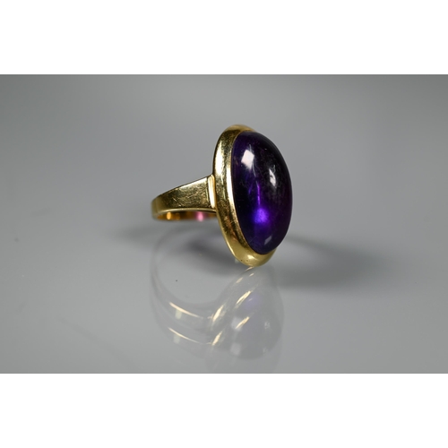 228 - A contemporary ring set with oval cabochon amethyst, yellow metal set stamped 750 Ka, size M, amethy... 