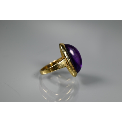 228 - A contemporary ring set with oval cabochon amethyst, yellow metal set stamped 750 Ka, size M, amethy... 