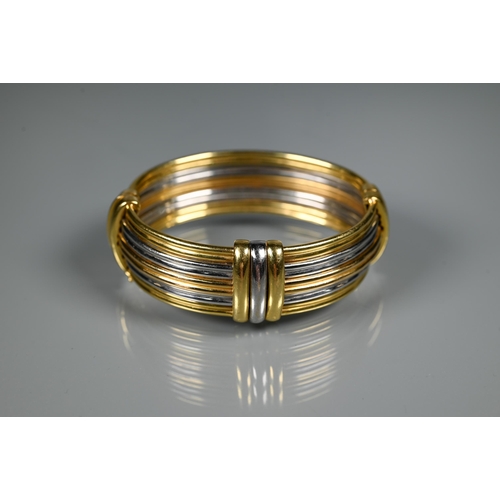 239 - A tri-coloured yellow metal oval bangle formed of five double reeded rows, concealed clasp, stamped ... 