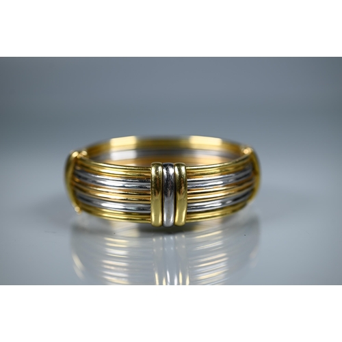 239 - A tri-coloured yellow metal oval bangle formed of five double reeded rows, concealed clasp, stamped ... 