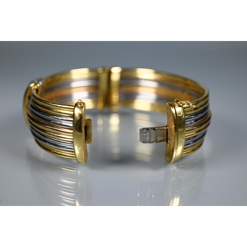 239 - A tri-coloured yellow metal oval bangle formed of five double reeded rows, concealed clasp, stamped ... 