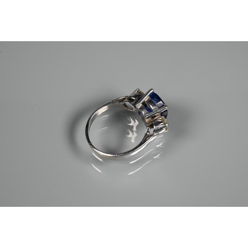 255 - A modern sapphire and diamond three stone ring, the central blue cushion cut sapphire with two round... 