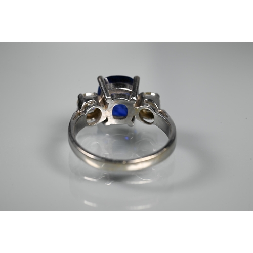 255 - A modern sapphire and diamond three stone ring, the central blue cushion cut sapphire with two round... 