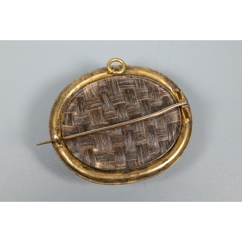 279 - A Victorian oval mourning brooch featuring plaited hairwork to front and back, the oval blue enamel ... 