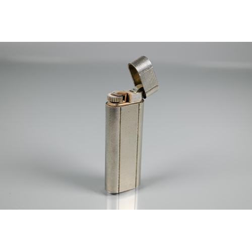 318 - Cartier - A silver-plated lighter of flattened cylindrical form, 7 x 2.5 cm