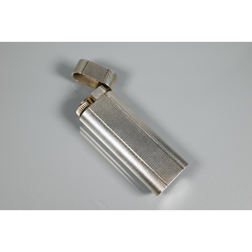 318 - Cartier - A silver-plated lighter of flattened cylindrical form, 7 x 2.5 cm