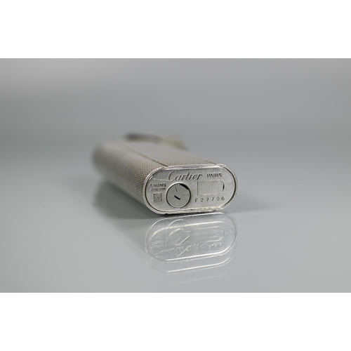 318 - Cartier - A silver-plated lighter of flattened cylindrical form, 7 x 2.5 cm