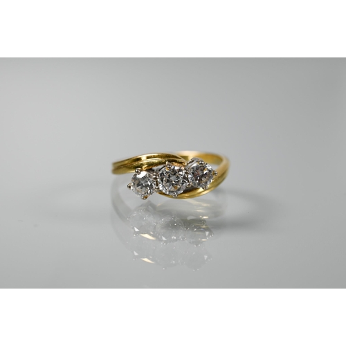 323 - An 18ct yellow and white gold three stone diamond cross-over ring, size K, diamonds approx 0.85 cara... 