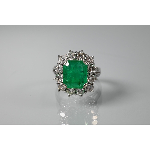 A rectangular cluster ring, the central natural emerald surrounded by twelve brilliant cut diamonds, the emerald approx 2.39 carats, gross weight 5.67g, white metal set, size K