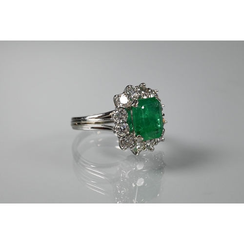 335 - A rectangular cluster ring, the central natural emerald surrounded by twelve brilliant cut diamonds,... 