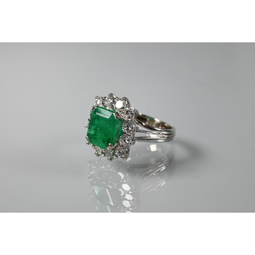 335 - A rectangular cluster ring, the central natural emerald surrounded by twelve brilliant cut diamonds,... 