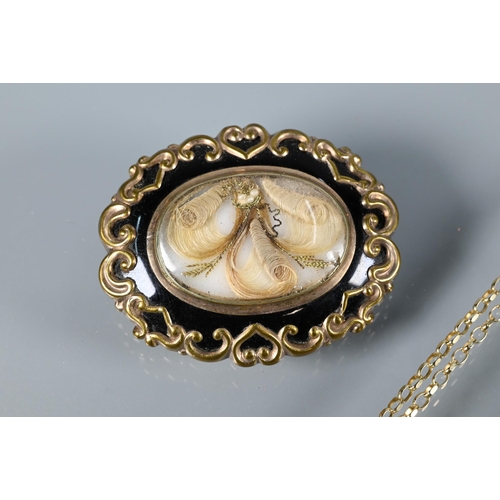 336 - A Victorian mourning brooch of oval scroll form, with hairwork plume beneath glass, the reverse insc... 