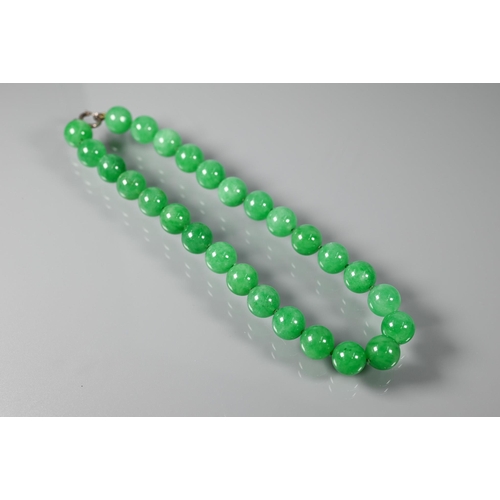 352 - A uniform row of green jade beads, double knotted throughout, each bead approx 1.4 cm diam, 41 cm lo... 