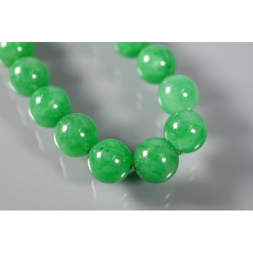 352 - A uniform row of green jade beads, double knotted throughout, each bead approx 1.4 cm diam, 41 cm lo... 