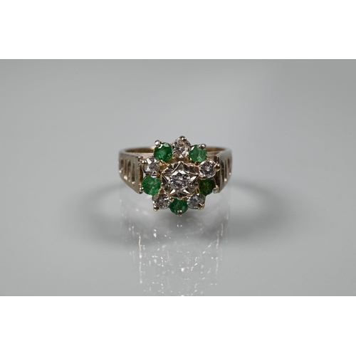 371 - A 1970s emerald and diamond cluster ring, the central bezel mounted diamond surrounded by five emera... 