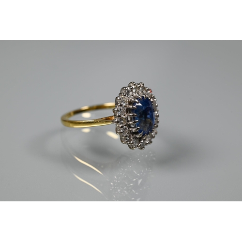 375 - An oval sapphire and diamond ring, the claw set blue sapphire surrounded by sixteen claw set diamond... 