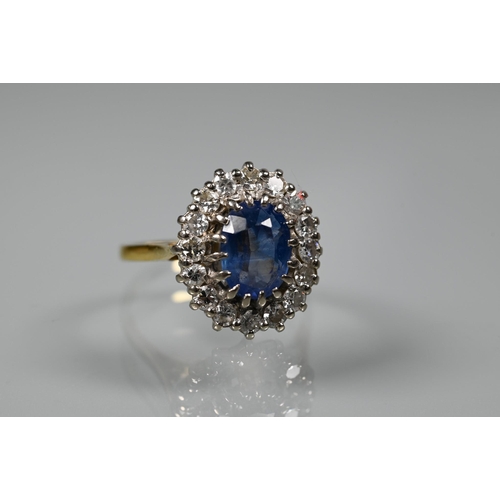 375 - An oval sapphire and diamond ring, the claw set blue sapphire surrounded by sixteen claw set diamond... 